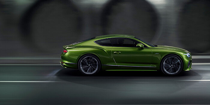  Bentley High Wycombe Bentley Continental GT coupe in Tourmaline Green paint driving in profile on a dark road