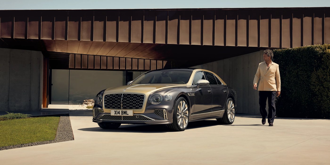 Bentley High Wycombe Bentley New Flying Spur Mulliner V8 hybrid sedan front three quarters in Rose Gold over Magnetic paint, parked near modern home