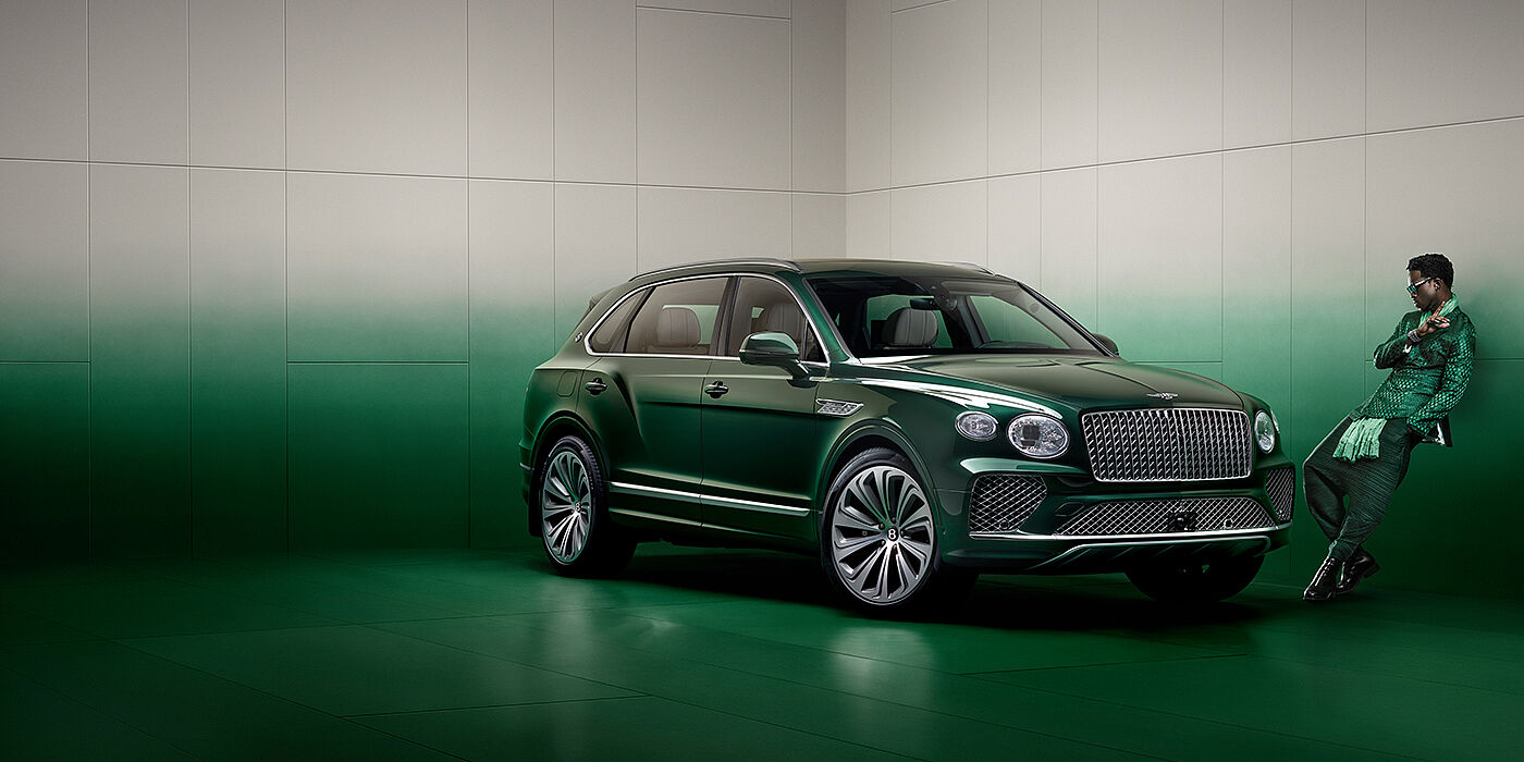 Bentley High Wycombe Wisdom K leans against wall next to Bentley Bentayga Extended Wheelbase Atelier Edition SUV in Light Emerald green paint