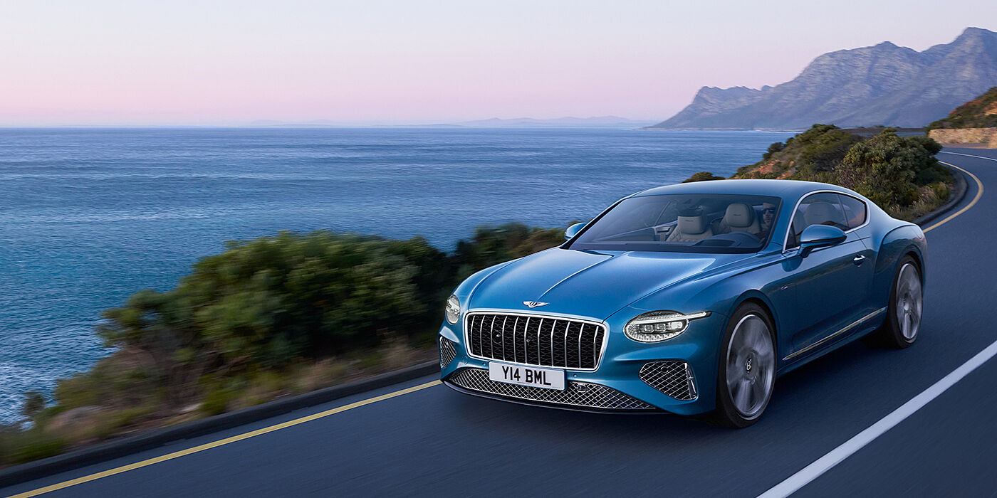 Bentley High Wycombe New Bentley Continental GT Azure coupe in Light Windsor blue paint with 22 inch Azure wheels and chrome grill, driving dynamically by the sea