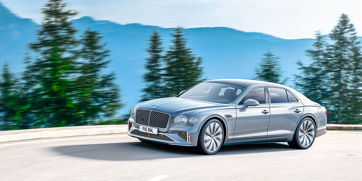 Bentley High Wycombe New Bentley Flying Spur sedan side view in Silverlake paint with ten spoke wheels and chrome matrix grille driving dynamically on a mountain road