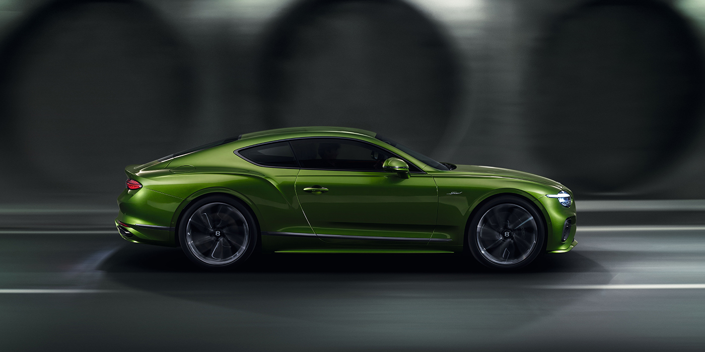 Bentley High Wycombe Bentley Continental GT coupe in Tourmaline Green paint driving in profile on a dark road