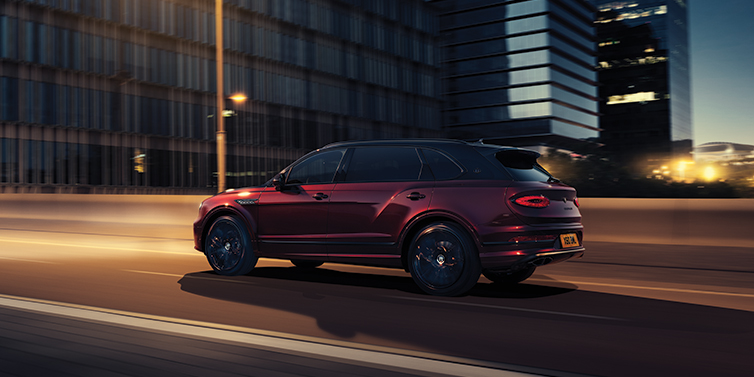 Bentley High Wycombe Bentley Bentayga Extended Wheelbase Mulliner SUV in Cricket Ball red paint driving dynamically in city at night